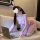 Woman in pink polka-dot bunny lingerie set with ears, choker, and gloves, kneeling beside laptop on couch.