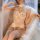 Woman wearing white pearl-accented pure & alluring bodysuit with veil, sheer stockings, and delicate lace details for sensual...
