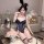 Woman wearing a navy blue lace bunny bodysuit with floral trim, open chest design, and fishnet stockings, posing with roses a...