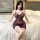 Woman wearing purple lace sleep dress on bed, sheer tempting lingerie with floral pattern and bow detail.