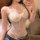 Woman wearing a white lace halter bodysuit with sheer panels, styled under jeans for a flirty layered look.