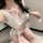 Woman wearing white pure & playful bunny girl costume set with pom-pom ties, sheer top and matching bottoms for cosplay.