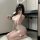 Woman kneeling in mirror selfie wearing white bunny girl lingerie jumpsuit with ears and fluffy tail for cosplay.