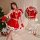A woman models a festive red and white christmas-themed lingerie set, featuring a flirty bralette with lace-up details and a ...