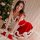 A woman poses beside a christmas tree wearing a festive red and white santa-themed lingerie set, featuring a flirty bralette ...