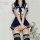 A woman models a japanese sailor uniform set, featuring a white crop top with navy blue accents, a matching pleated skirt, an...