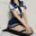 A woman wearing a navy blue and white sailor uniform set, featuring a cropped top with a sailor collar and pleated skirt, pai...