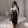 Woman in black satin chemise nightgown with adjustable straps, holding wine glass, posing on bed—seductive sleepwear for wome...