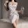Woman in white satin pure & playful lace chemise nightgown with adjustable straps, holding wine glass on bed.