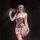 Woman wearing red and black lace lingerie set with bows and pearl bodysuit, holding a wand in a dimly lit room.