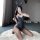 A woman poses on a fluffy rug wearing a black bunny costume bodysuit with fishnet stockings, capturing a playful moment indoo...