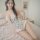 A woman poses on a bed wearing a floral lace bodysuit from pure & playful, featuring adjustable straps and a no-remove design...
