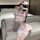 Woman in pink nurse-themed lingerie set with crop top, skirt, and lace stockings on a couch.
