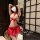 Woman wearing red and white pure & playful lingerie set with jk-style skirt, lace bralette, and bow accents in modern room.