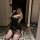 Woman kneeling in a black, sheer pure & playful lingerie set with cat ears, taking a mirror selfie.