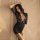Woman in black lace lingerie set with deep v-neck and sheer sleeves, posing seductively against soft beige backdrop.