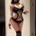 Woman modeling black lace pure & playful lingerie set with strappy bodysuit, choker, and thigh-high stockings.