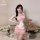 A woman poses with a teddy bear, wearing a pink sheer sleepwear set featuring a nurse apron design. the outfit combines playf...