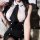 Woman in white and black pure & playful lingerie set, featuring a deep v-neck top with bow tie and buttoned skirt.