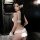 Woman wearing white lace lingerie set with choker and hair accessories, back view in dark room.
