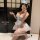 A woman poses in a maid-themed lingerie set, featuring a plaid dress with lace details and stockings, capturing playful elega...