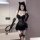 Woman wearing black lace lingerie set with corset vest, cat ears headband, gloves, and thigh-high stockings.