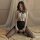 Woman wearing pure & playful lingerie sleep set – sexy black nightgown with lace top, sheer stockings, on bed.