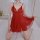 Woman wearing red sheer lingerie sleep dress with lace detailing, kneeling on bed in romantic bedroom setting.