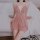 Woman wearing pink sheer lingerie sleep dress with lace detailing, sitting on bed – pure & playful romantic nightwear set.