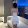 Woman in white sheer silk-look babydoll sleep dress with adjustable straps, back view, playful cat ears, modern room.