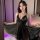 Woman wearing black lace sleep dress from pure & playful lingerie set, sheer fabric flowing, soft lighting, bedroom setting.