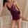 Woman wearing purple lace sleep dress from pure & playful lingerie set, posing beside tufted sofa in soft bedroom setting.