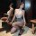 Woman wearing pure & playful secretary costume set with lace top, bodycon skirt, and sheer tights, kneeling beside mirror in ...