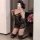 Woman kneeling in mirror selfie wearing black lace sleep dress with sheer babydoll design and adjustable straps.