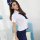 A woman wearing a white blouse with a navy blue tie and matching cap, paired with a fitted navy skirt, posing elegantly. perf...