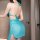 Woman wearing a turquoise lace bodysuit dress with a french-style cutout wrap mini skirt and neck tie, showcasing the back vi...