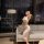 Woman in sheer lace bodysuit dress, elegant sleepwear set, posing by window at night.