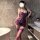 Woman wearing purple pure & seductive lace bodysuit with matching thigh-highs in modern bathroom setting.