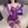 Woman wearing purple pure & seductive lace bodysuit with matching gloves and stockings, posed on bed beside laptops.
