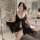 A woman poses in a luxurious bathroom wearing a sheer black lace chemise, part of a romantic lingerie set designed for couple...