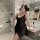A woman poses in a luxurious bathroom wearing a black lace chemise, featuring sheer transparent design ideal for romantic cou...