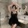 A woman poses in a luxurious bathroom wearing a black lace chemise, featuring sheer fabric and elegant design, perfect for ro...