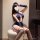 A woman poses confidently wearing a navy blue lace halter airline uniform set, featuring a deep neckline and thigh-high stock...