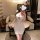 Woman wearing a white lace lingerie set with black polka dots and bows, styled as outerwear in a cozy room setting.