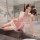 Woman in pink lace sleep dress with satin blend, adjustable straps, posing elegantly on bathroom counter.