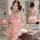 Woman wearing pink lace sleep dress with ruffles and bow, shown front and back view in bathroom setting.
