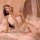 Woman wearing white sheer mesh babydoll nightgown with adjustable straps, lying on bed in sensual bedroom lingerie set.