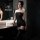 A woman poses elegantly in a black sheer bodysuit, featuring a strapless design and lace stockings, perfect for intimate mome...