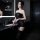 A woman poses elegantly in a black sheer bodysuit with lace detailing, perfect for intimate moments. the outfit features a st...