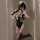 A woman poses in a black lace maid costume with stockings, capturing a playful moment. the outfit features delicate lace deta...